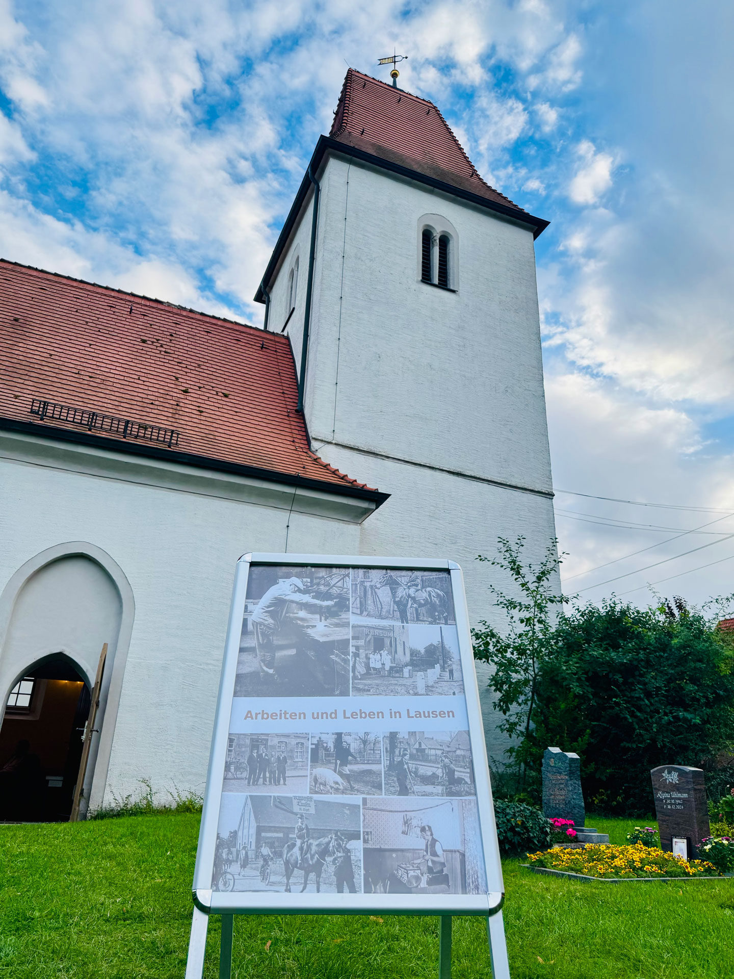 Kirche Lausen mit dem Aufsteller für die Ausstellung Arbeiten und Leben in Lausen